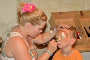Cheryl face painting a child as a lion.