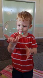 Child holding a big bubble.